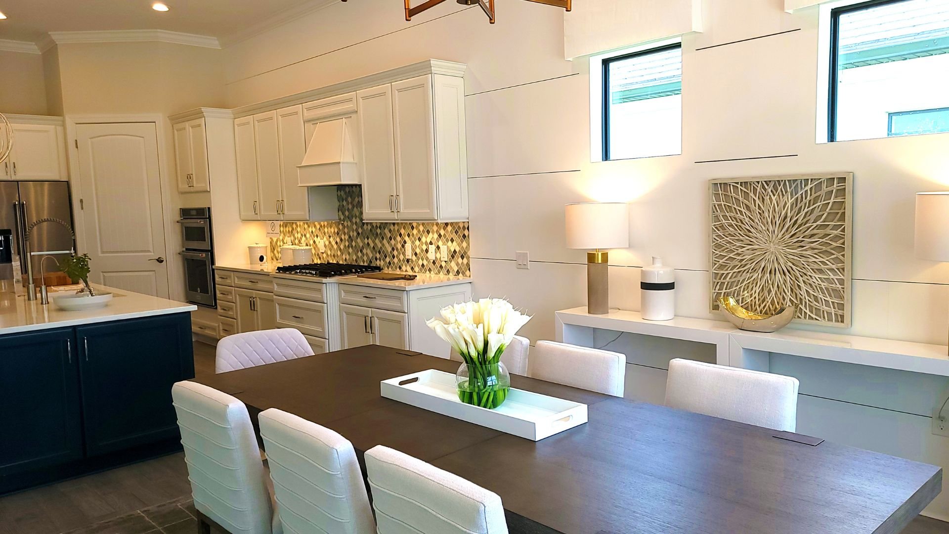 Modern kitchen with white cabinets, dark table, and white tulips centerpiece