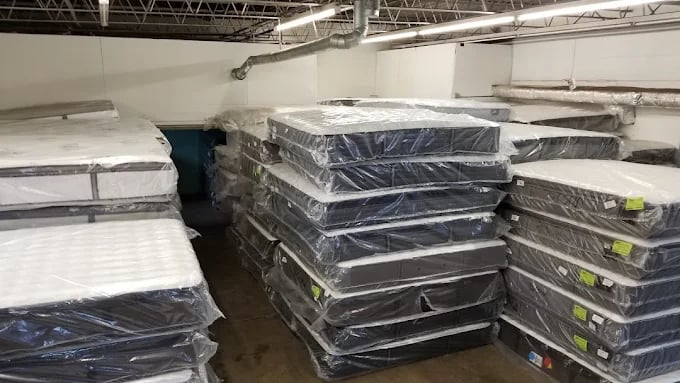 Stacks of new mattresses wrapped in plastic in a warehouse storage area